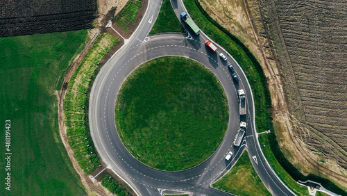 Roundabout traffic of cars and trucks on the circle ring road aerial top view