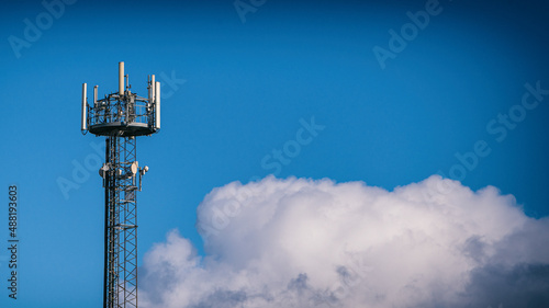 Mobilfunkmast vor blauem Himmel mit Wolke photo