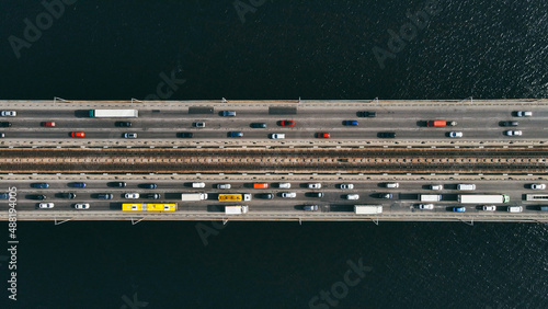 Aerial top view of cars and subway passing the bridge over the river in the city