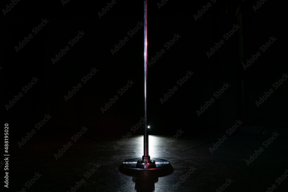 Pole dance in studio at black background. Striptease night club. Stock