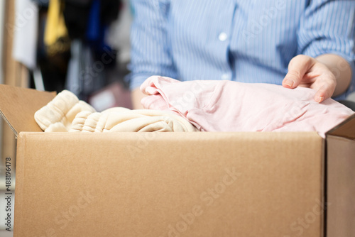 wardrobe order, house cleaning, a woman takes clothes out of the closet, puts them in boxes