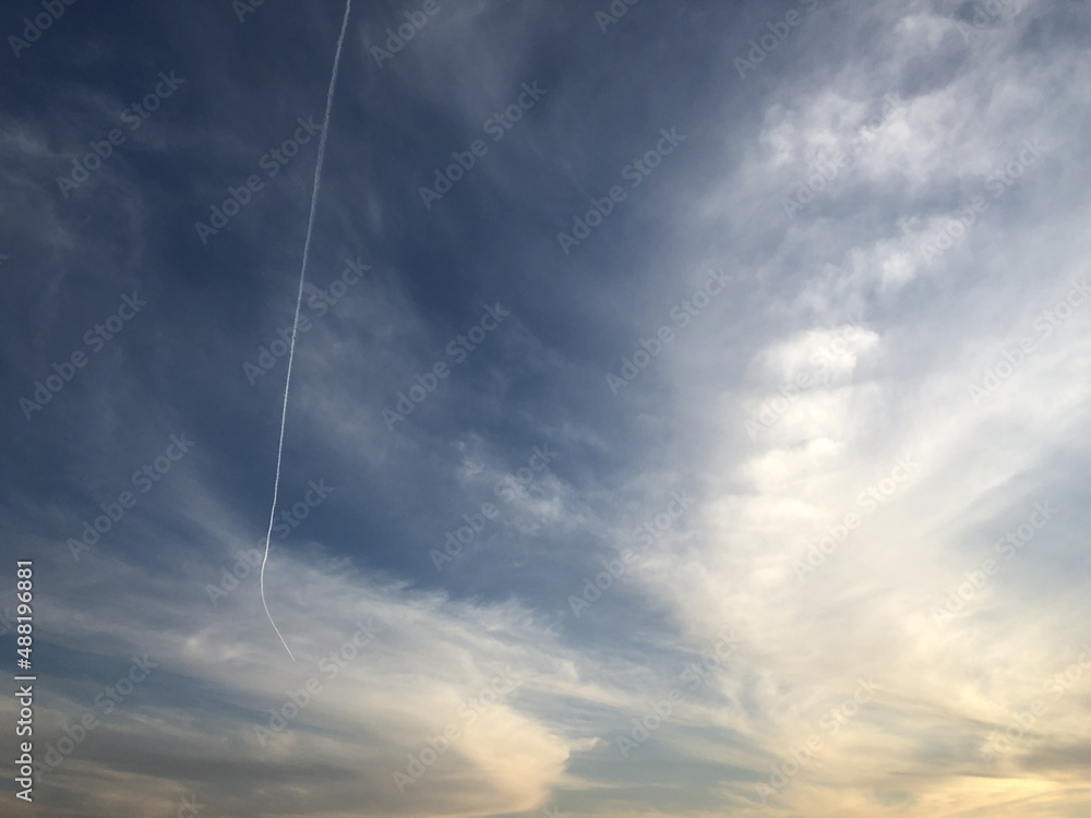 A chemtrail in a cloudy sky. An airplane trail in a sky. Jet. Ecology. Environment. Evening sky. Clouds. Haze A chemtrail in a cloudy sky. An airplane trail in a sky. Jet. Ecology. Environment. Evening sky. Clouds. Haze
