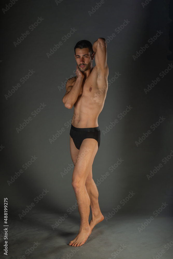 Sexy man with a muscular body posing naked with black underpants inside a studio