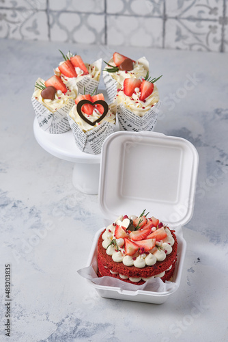 Gift set for the holiday. Red velvet bento cake with fresh strawberries and red velvet cupcakes with strawberries, chocolate and cream cheese cream.