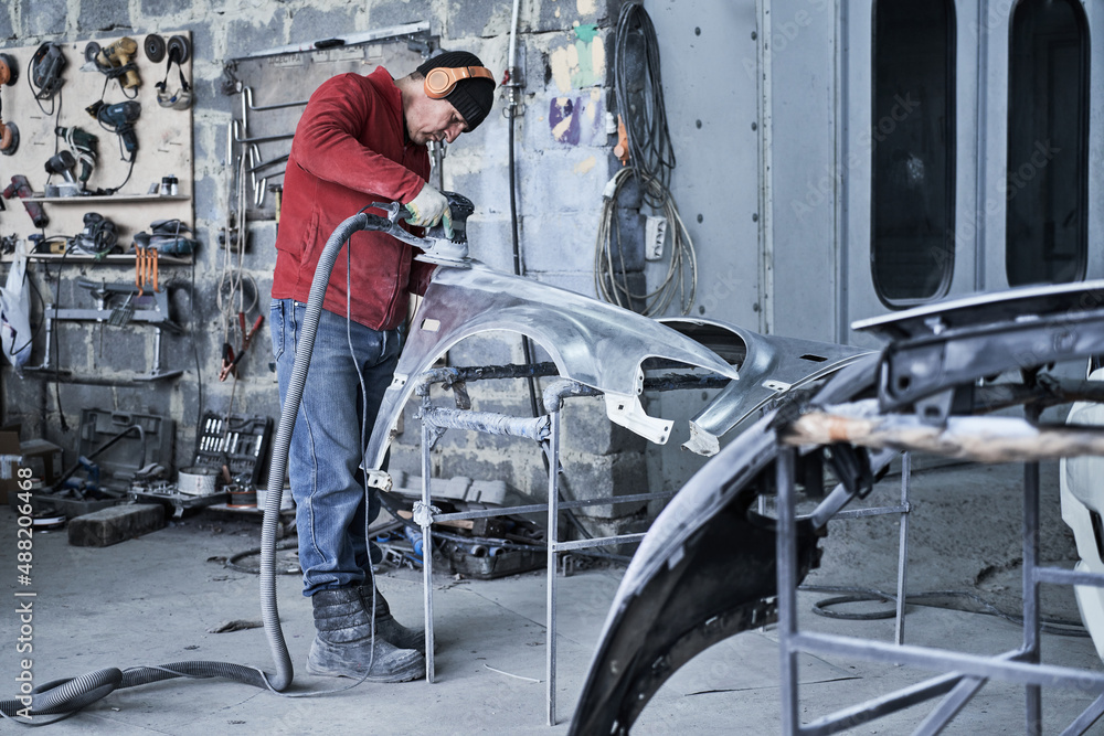 Car service worker repairs restores car