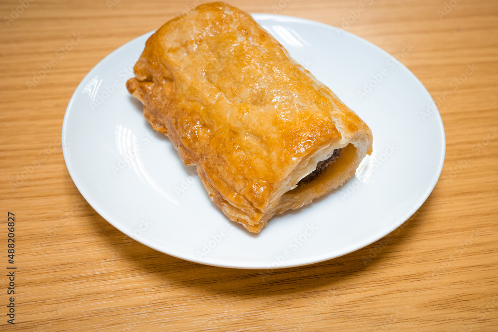 A fresh from the oven homemade rustic sausage roll on a white plate A fresh from the oven homemade rustic sausage roll on a white plate