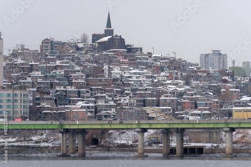 Snowy church and neighborhood in Seoul. The snow cover the roofs on a gray day of winter.
