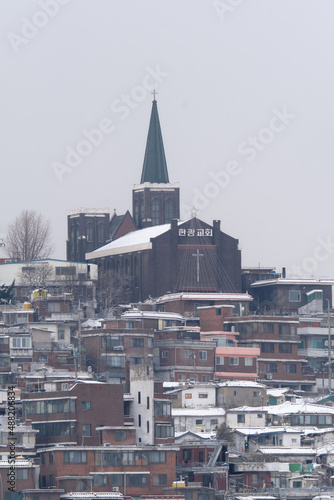 Snowy church and neighborhood in Seoul. The snow cover the roofs on a gray day of winter.