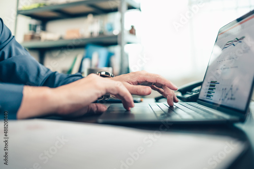 Business man working, typing on laptop at office with document report, graph, financial report.