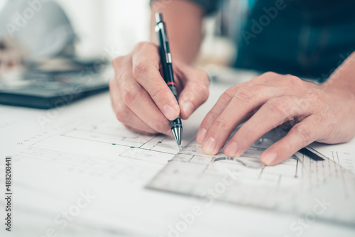 Architect engineer use pen and triangular angle ruler drawing design working on blueprint. House planning design and construction concept.