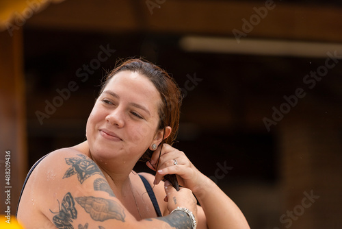 tattooed style girl smoothing her hair, dark blurred background