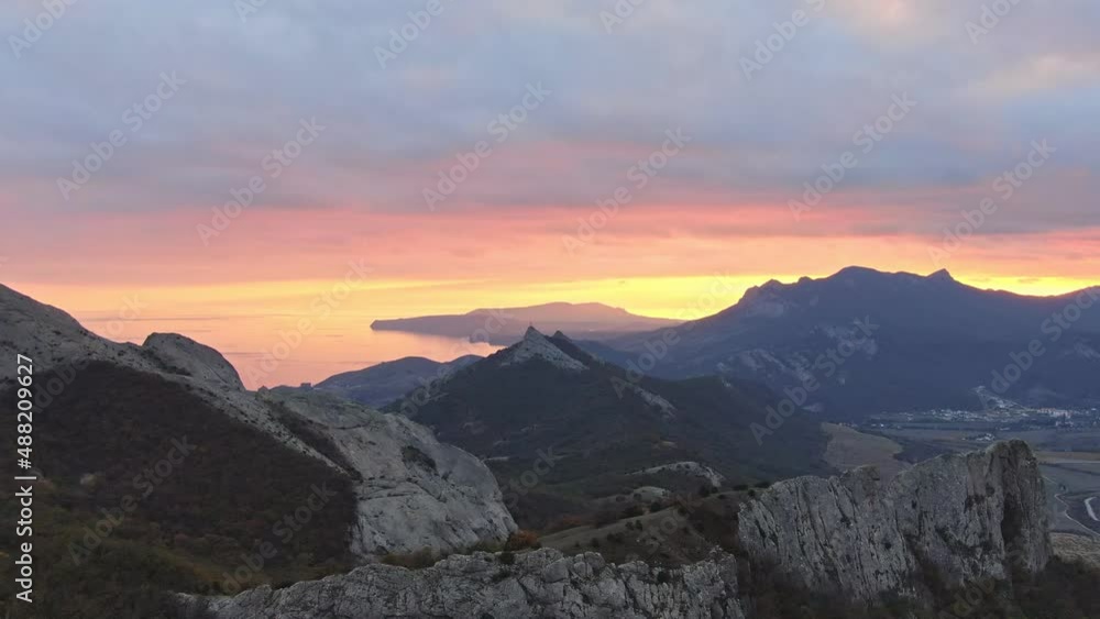 A bright orange sunset over a coastal mountain range under an overcast sky with clouds. Amazing spectacle aerial view and slow motion A bright orange sunset over a coastal mountain range under an overcast sky with clouds. Amazing spectacle aerial view and slow motion