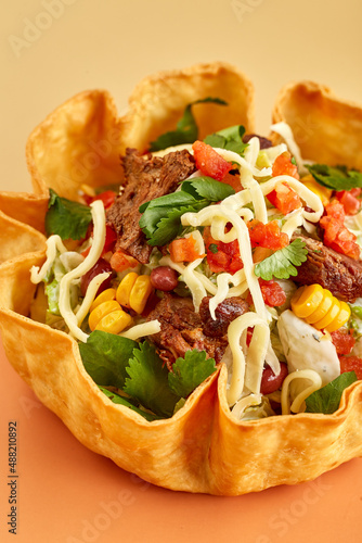 Taco salad in tortilla bowl with beef, cheese, corn and lettuce