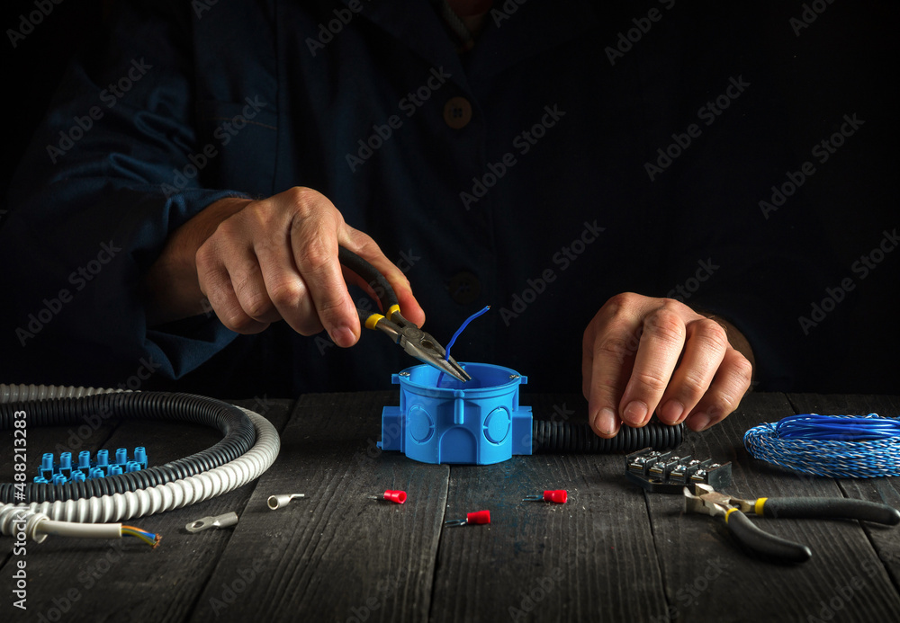 The master electrician installs the cable or wires into the blue junction box. The idea of repairing electrical equipment