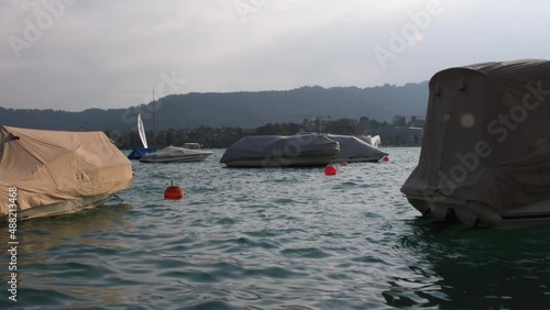 Boats, sailing yachts on lake Zurich, Switzerland. Landscape. View of the opposite bank with houses on the slope, swiss alps mountains on background, 4k video