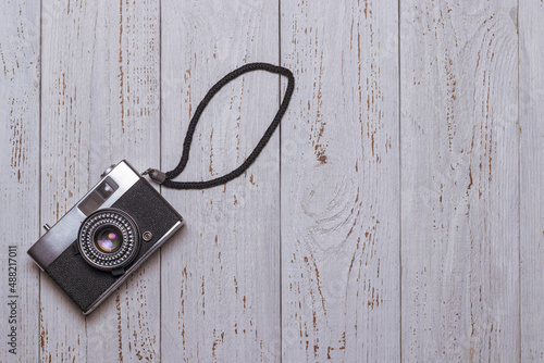 Old retro camera with hand strap on white wooden table © Franchesko Mirroni