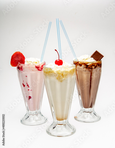 Delicious chocolate, strawberry and vanilla milkshakes on white background
