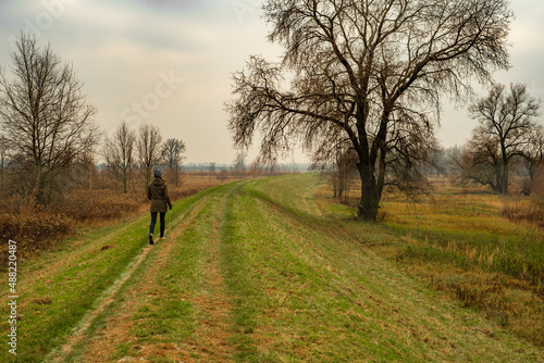 Nordic walking - a woman who walks along a flood embankment