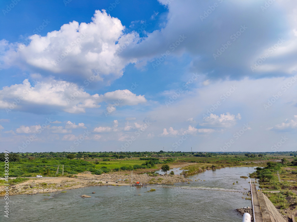 Scenic view of Bennithora river, small walk way or pathway in the middle of the river, vehicles moving forward. Few people standing on roadway, blue sky with white clouds on background.