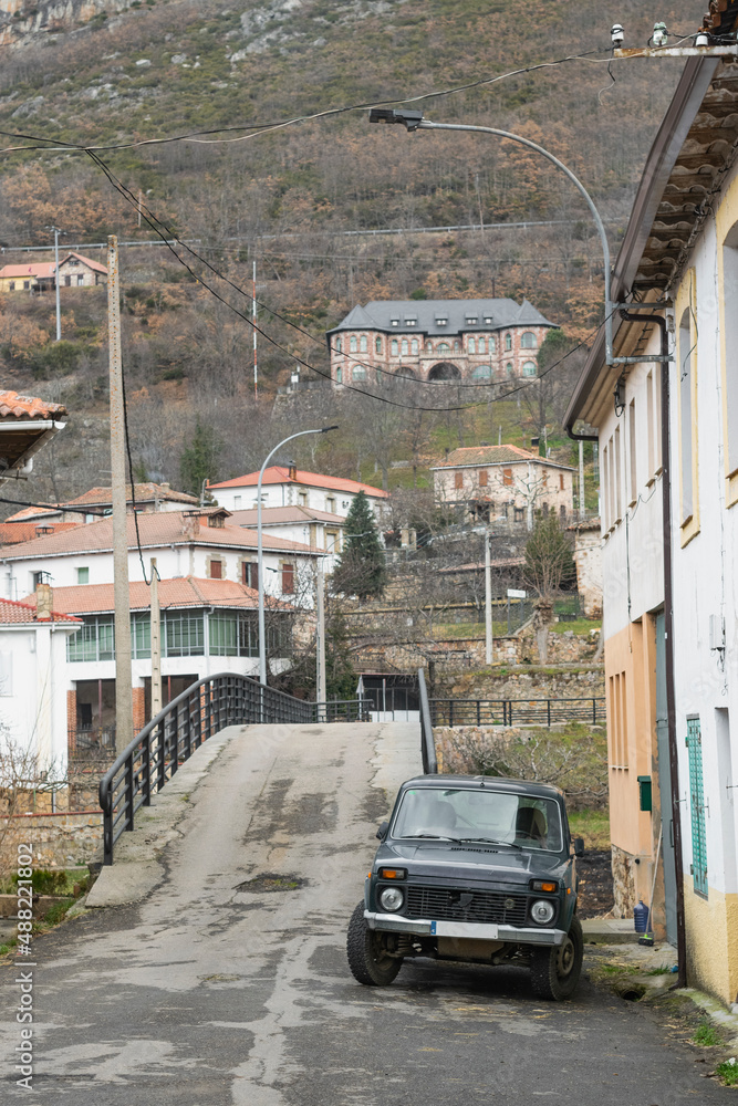 Fototapeta premium Coche viejo aparcado en la puerta de una casa en un pueblo poco transitado