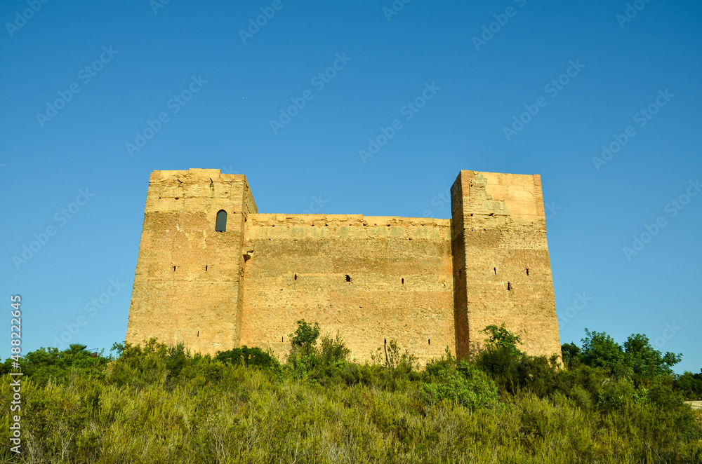 The castillo de forna on a big rock surrounded by green trees and bushes under blue sky