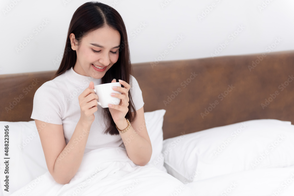 Beautiful asian woman Drinking coffee And happy smile On the bed in the white bedroom Beautiful asian woman Drinking coffee And happy smile On the bed in the white bedroom