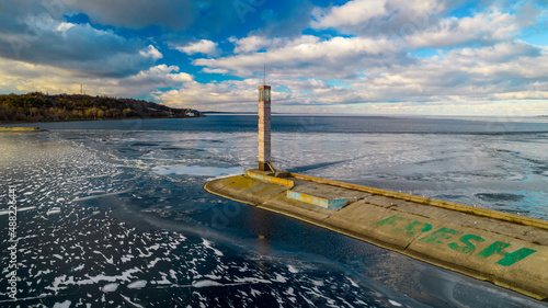 Aerial view of a pier with a lighthouse on a frozen lake