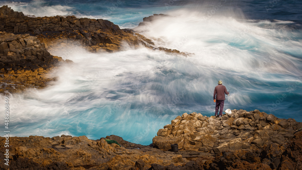 Obraz premium fisherman in the turbulent waters of the atlantic ocean,
