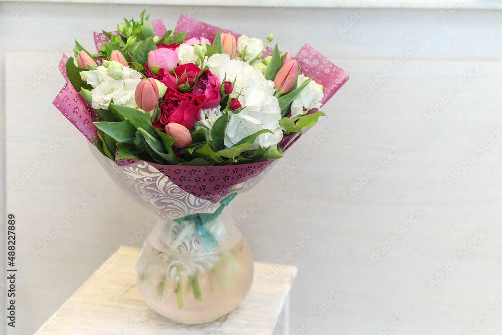 Naklejka premium Wedding bouquet of red roses, white hydrangea, pink tulips and lisianthus for various occasions for sale in the store