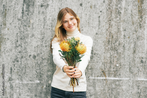 Bouquet of yellow leucospermum flowers holding by young teenage girl, selective focus photo