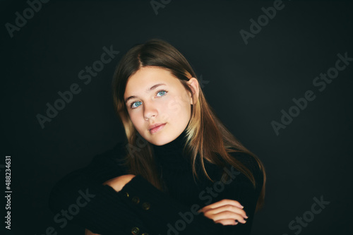 Studio portrait of pretty young teenage girl posing on black background