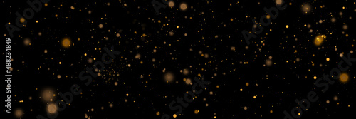 Glowing light effect in yellow gold color with lots of shiny particles isolated on dark background. Vector star cloud with dust.	

