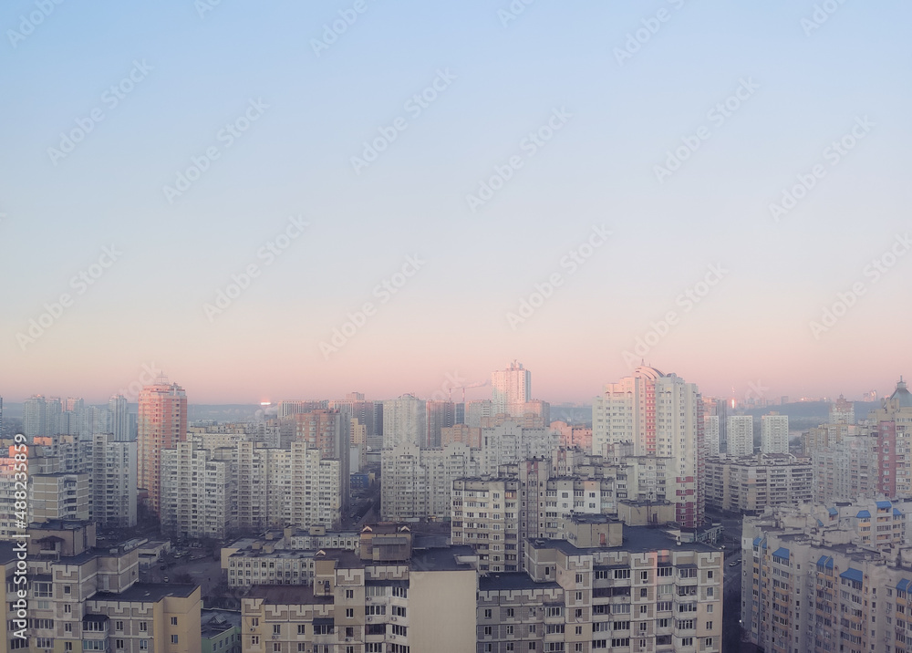 Obraz premium Cute, pink sky without clouds at sunrise over morning city. Clear heaven background is pastel, subtle and gentle. Town in aerial perspective at evening, sunset.