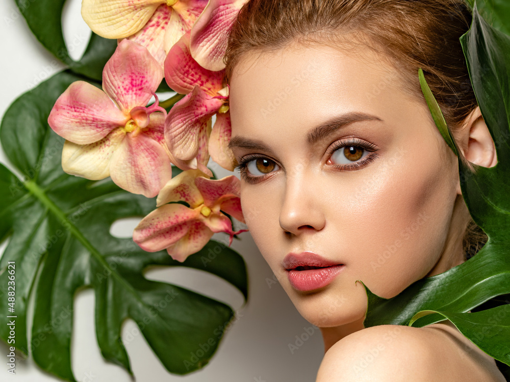 Beautiful woman with green leave near face and body. Closeup girl's face with green leave. Pretty girl in Skin care beauty treatments concept. Model with pink tropical orchid near face. Brown makeup. Beautiful woman with green leave near face and body. Closeup girl's face with green leave. Pretty girl in Skin care beauty treatments concept. Model with pink tropical orchid near face. Brown makeup.