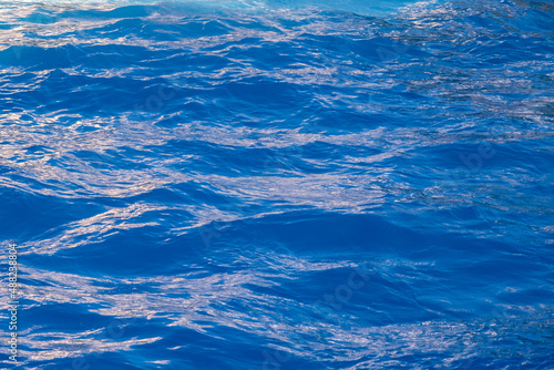 Vivid, bright ripple texture. Aqua blue color water surface. Vacation near sea, okean. Copy space, top view.