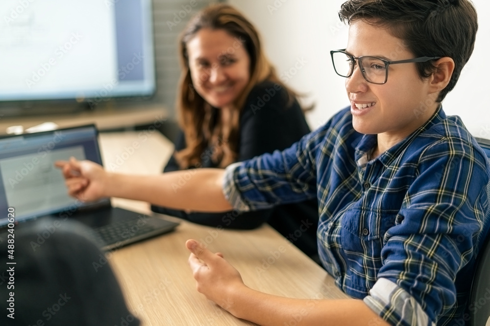 Young intern.A young man explaining something at the meeting and pointing the finger in to the lap top Young intern.A young man explaining something at the meeting and pointing the finger in to the lap top