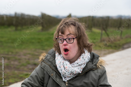 Hakendover, Flanders  Belgium -Portrait of white woman with Down Syndrome and myopia who looks at the other side with open mouth and surprised expression photo