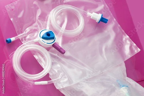 Devices for daily self-care CAPD (continuous ambulatory peritoneal analysis) treatment. Tubing system and drainage bag on dialysate bag on pink background photo
