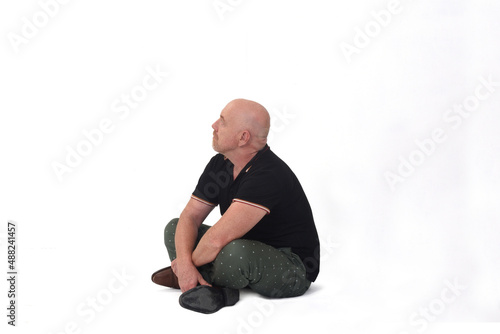 side view of man sitting on floor looking up on white backgound