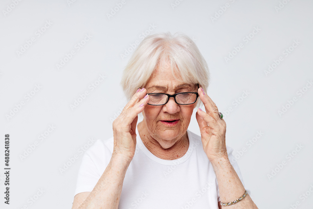 Photo of retired old lady in casual t-shirt and glasses light background Photo of retired old lady in casual t-shirt and glasses light background