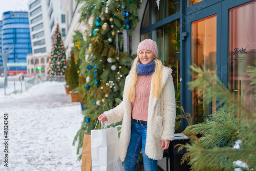 girl going out of the store with purchases on the background of Christmas fir. sale © Olleg1