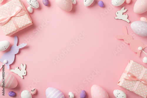 Top view photo of easter decorations gift boxes easter bunnies pink lilac and white easter eggs on isolated pastel pink background with copyspace in the middle © ActionGP