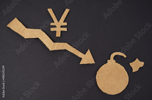 Concept of economic crisis. On a black surface is a graph with a down arrow, a yen symbol and a bomb. photo