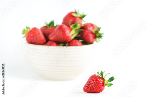 Fresh red strawberries with green leaves on white background.