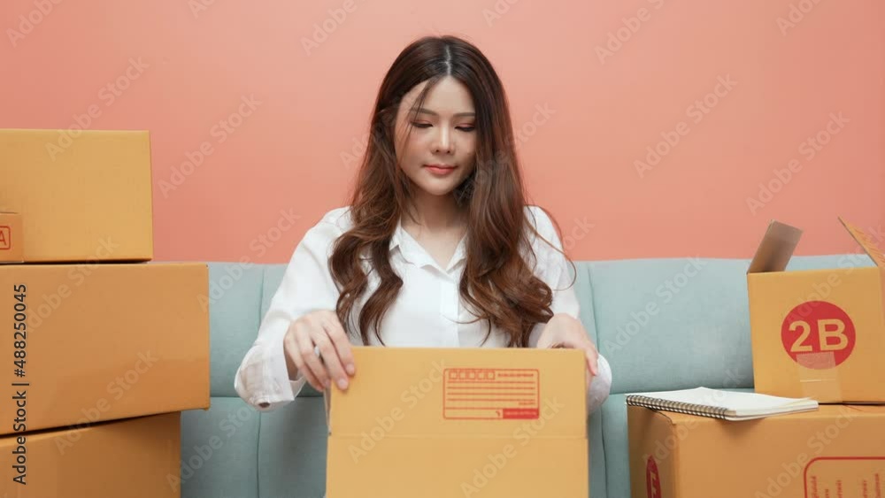Business concept of 4k Resolution. Asian woman packing products in boxes at home. Business concept of 4k Resolution. Asian woman packing products in boxes at home.