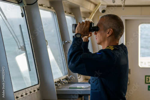 Obraz na plátne Deck officer with binoculars on navigational bridge