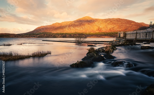 Fototapeta Naklejka Na Ścianę i Meble -  Beautiful cloudy sunrise landscape scenery with lake and mountains at Derryclare natural reserve in Connemara National park, county Galway, Ireland 