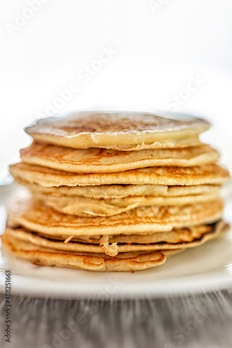 Macro closeup side view of stack of buttermilk plain pancakes on plate as traditional breakfast brunch dessert