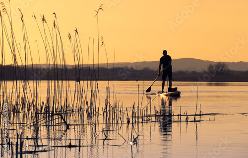 Silhouetted man stand up peddle boarding at sunset on river Corrib in Galway  Ireland 