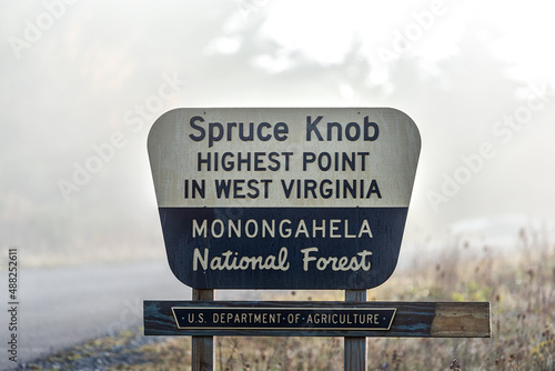 Sign closeup at Spruce Knob West Virginia mist fog autumn fall season by empty road for highest point in Monongahela national forest Appalachian mountains photo